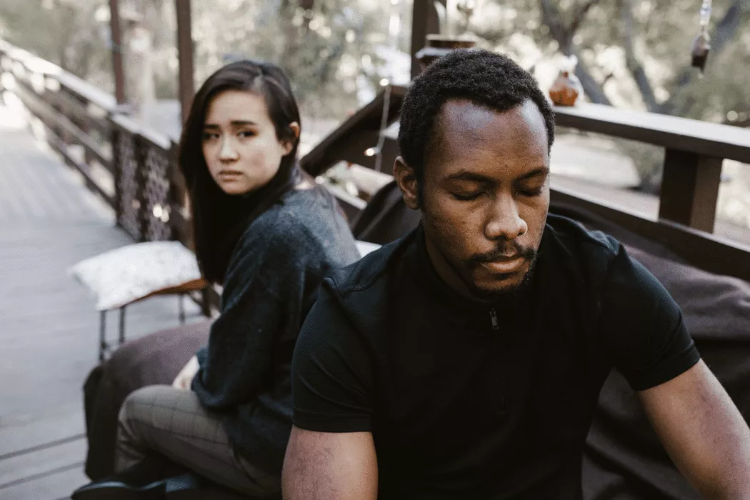 A somber couple sitting apart on an outdoor bench, conveying tension and emotional distance, representing family legal challenges in Toronto.