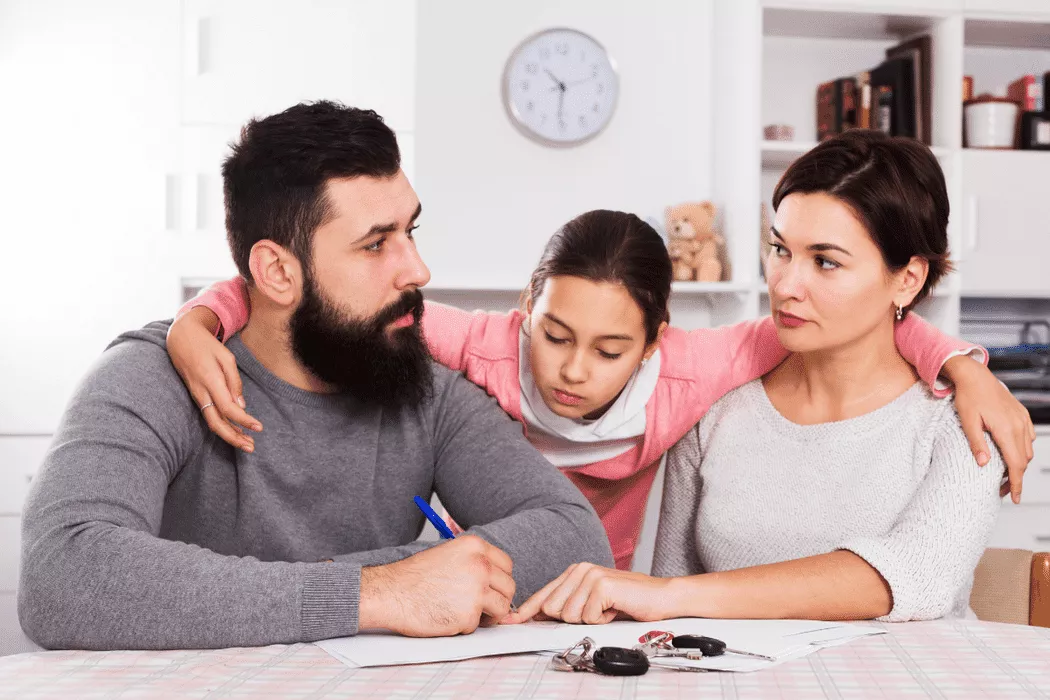 Concerned family with young daughter sitting at a table discussing legal documents, symbolizing support from Nussbaum family lawyers in Toronto for family legal matters.